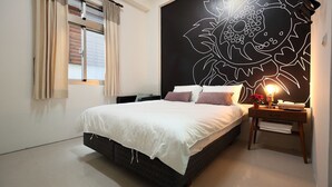 A modern bedroom with a large bed, a nightstand with a lamp, and a wall mural. - A-Ba Homestay  (Hualien City)
