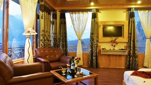 A cozy room with a brown leather sofa, a wooden coffee table, and a TV mounted on the wall. - Whistling Pines Resorts and Spa (Manali)
