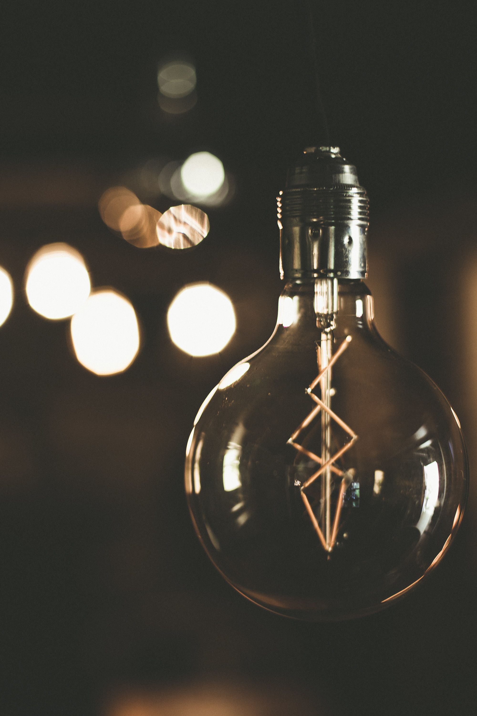 A clear glass bulb with a geometric design inside, hanging from a metal fixture.