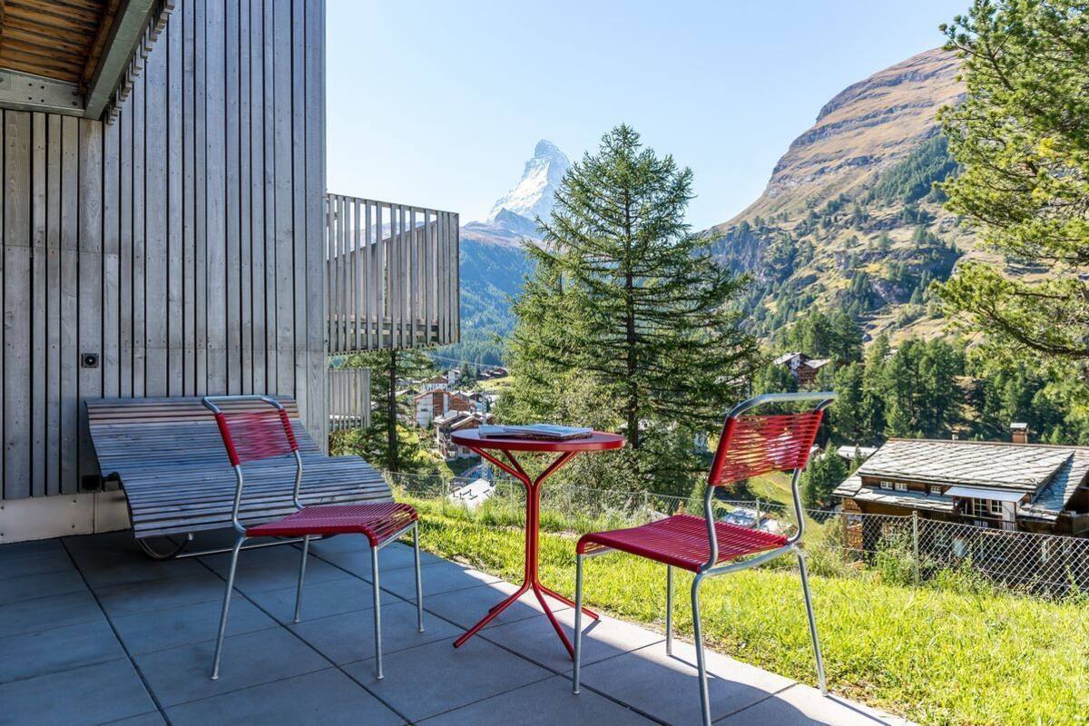 A balcony with a view of mountains and a small building in the background.