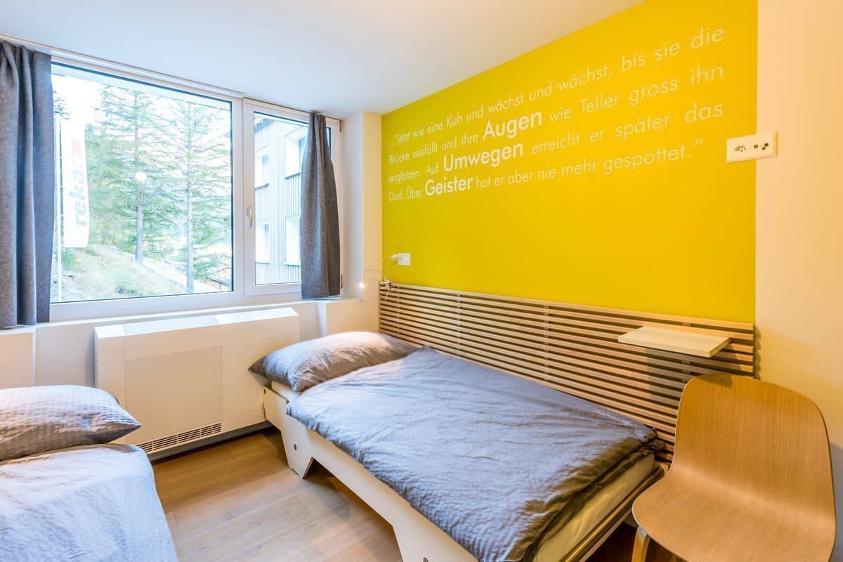 A room with a bed, a chair, and a window with curtains.