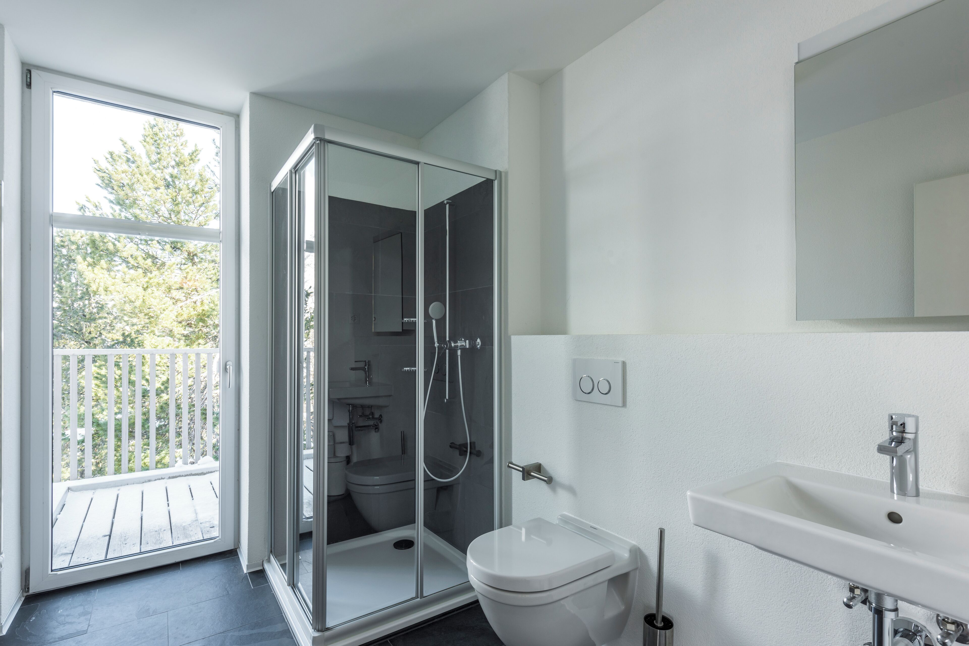 A modern bathroom with a glass-enclosed shower, a toilet, and a sink.