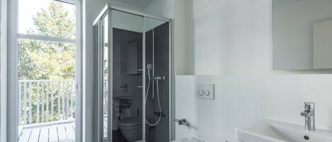 A modern bathroom with a glass-enclosed shower, a toilet, and a sink.