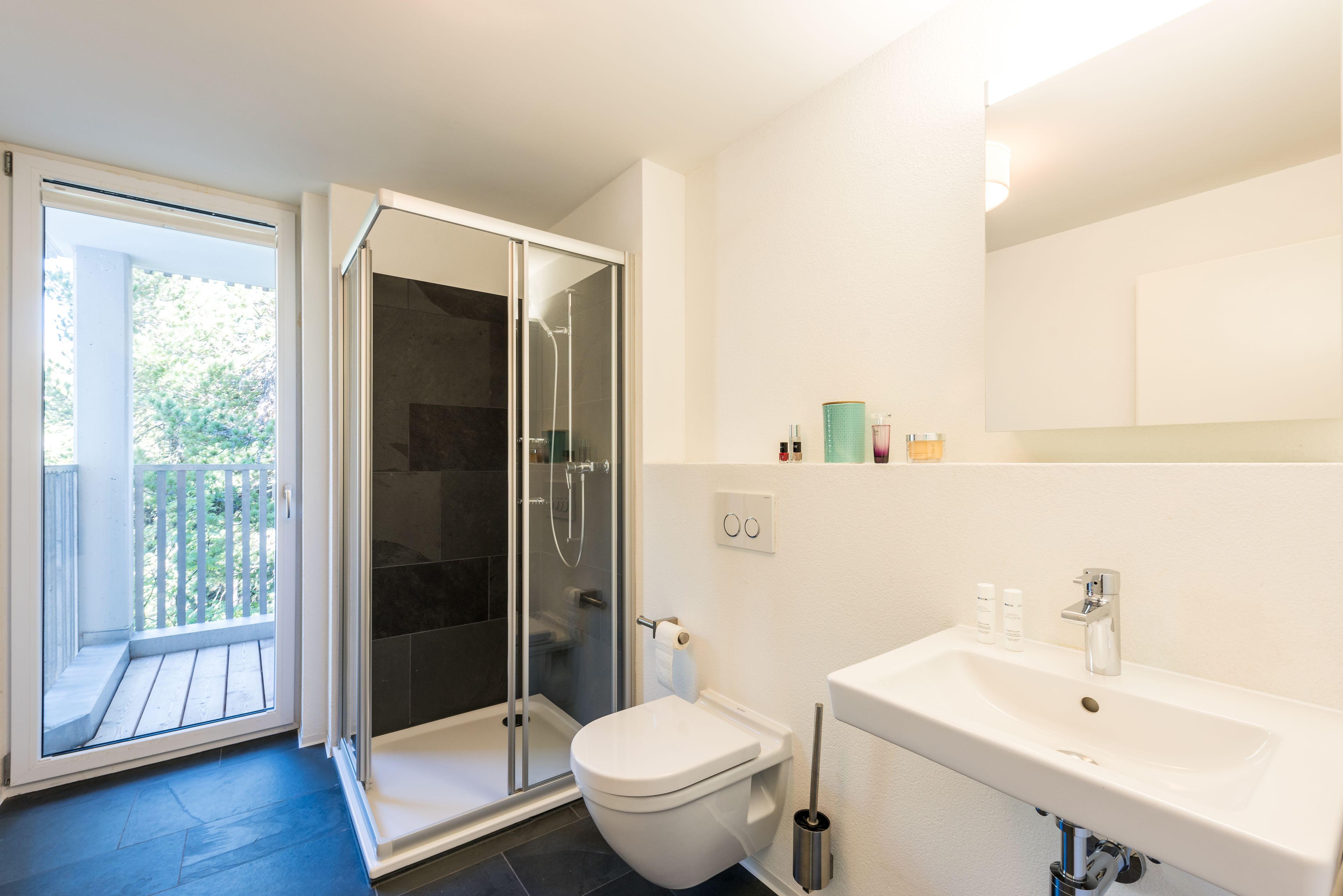 Een moderne badkamer met een glazen douchecabine, toilet en wastafel.