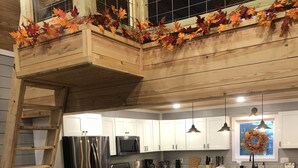 Una cocina con armarios blancos, una mesa de madera y un banco.