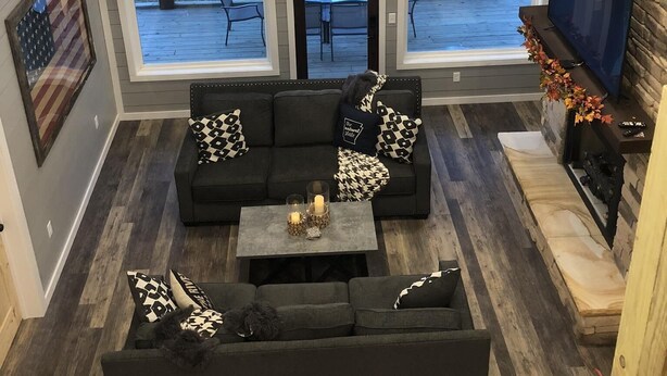 Un salón espacioso con techo alto, ventanas amplias, chimenea y televisor.
