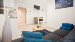 Ein modernes Wohnzimmer mit einer Couch, einem Couchtisch und einem Essbereich mit Stühlen.