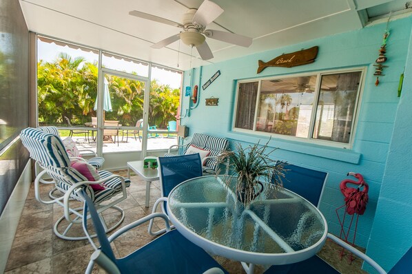 A room with a glass table, striped chairs, a ceiling fan, and a view of the outdoors. - Super comfy cottage, close to the beach (Nokomis)