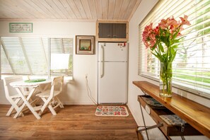 A compact kitchen with a white refrigerator, wooden cabinets, a dining table with chairs, and a window with blinds. - Super comfy cottage, close to the beach (Nokomis)