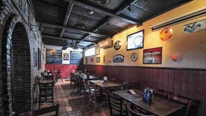 A restaurant interior with brick walls, wooden tables, and chairs. - Beautiful 1BD Apt with Roofdeck in Passyunk Square (Philadelphia)