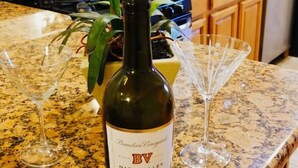 A kitchen counter with a wine bottle, two wine glasses, and a vase with flowers. - Beautiful 1BD Apt with Roofdeck in Passyunk Square (Philadelphia)