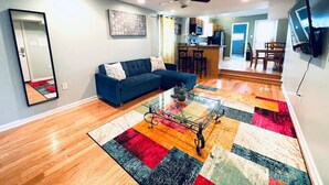A living room with a blue sofa, a glass coffee table, and a colorful rug. - Beautiful 1BD Apt with Roofdeck in Passyunk Square (Philadelphia)