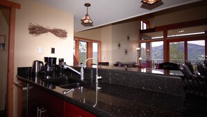A modern kitchen with a granite countertop, stainless steel appliances, and a large window offering a view of the outdoors.
