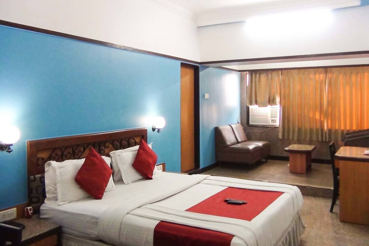 A hotel room with a bed, a desk, a chair, and a window with curtains.
