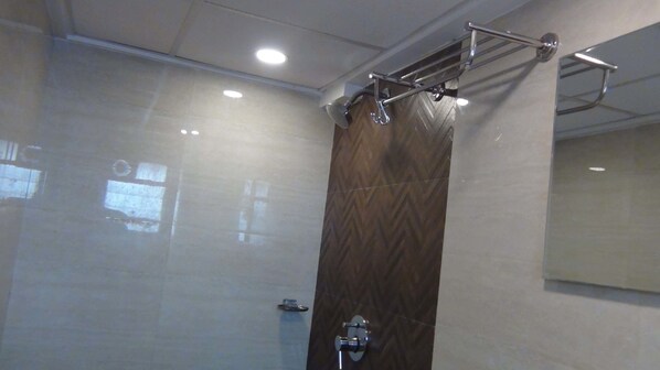 A modern bathroom with a glass shower enclosure, a wooden panel wall, and a mirror.
