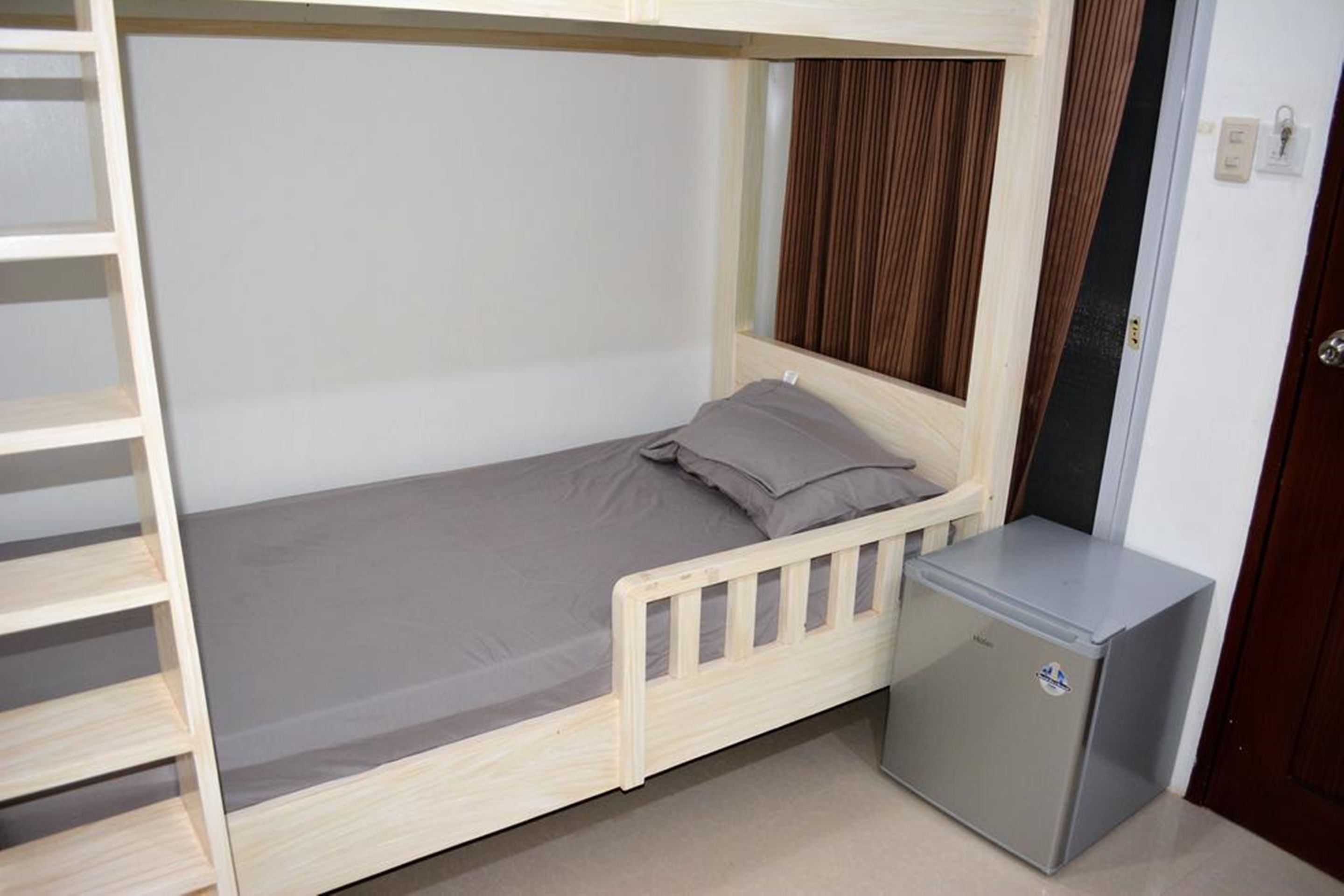 A bunk bed with a small attached desk and a refrigerator.