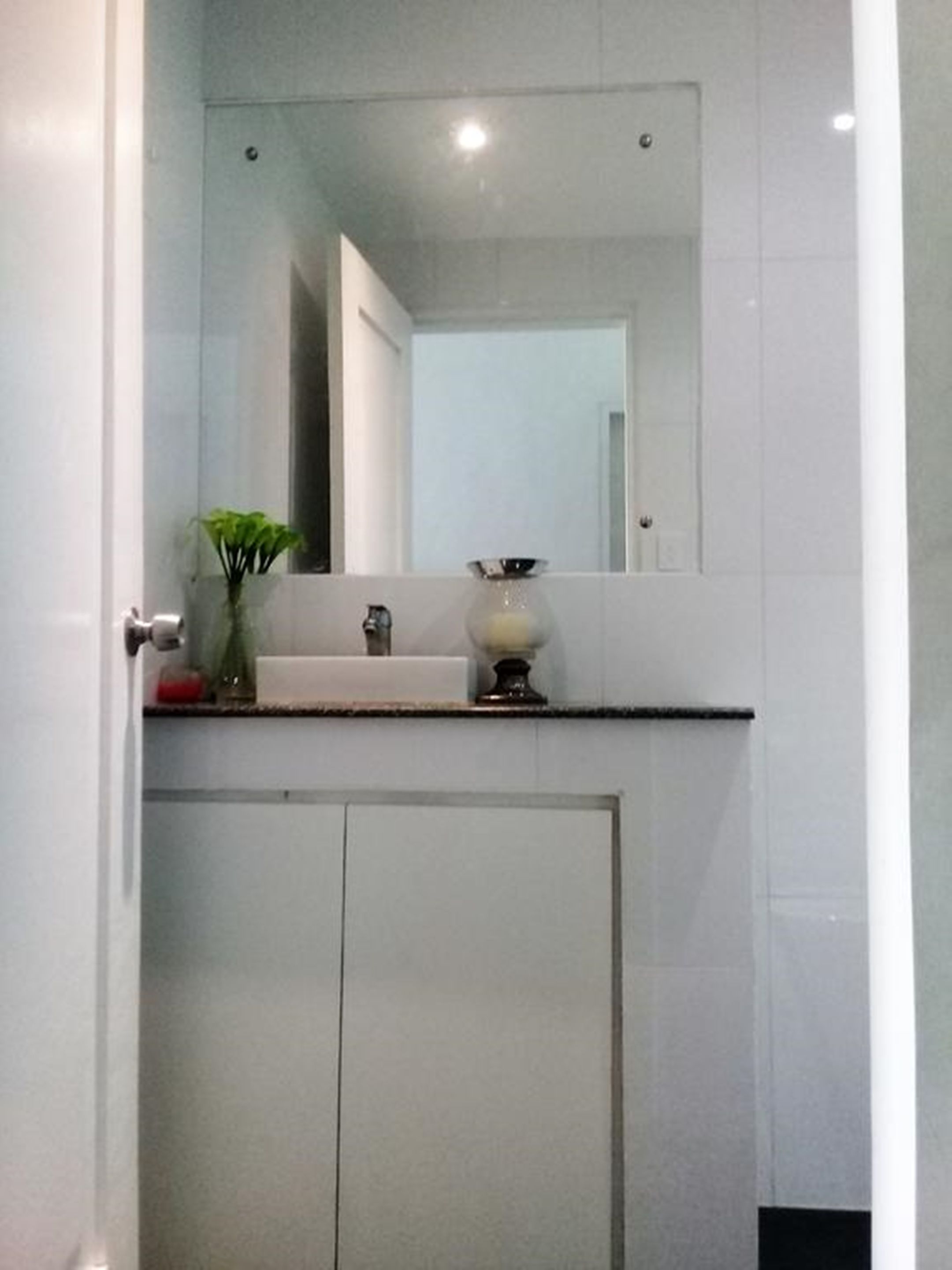 A bathroom with a mirror, sink, and cabinets.