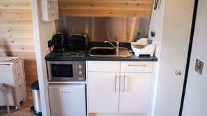 Een praktische keuken met een magnetron, broodrooster, spoelbak en een kleine koelkast.