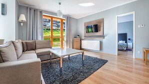 Een moderne woonkamer met een bank, salontafel en een tv aan de muur.