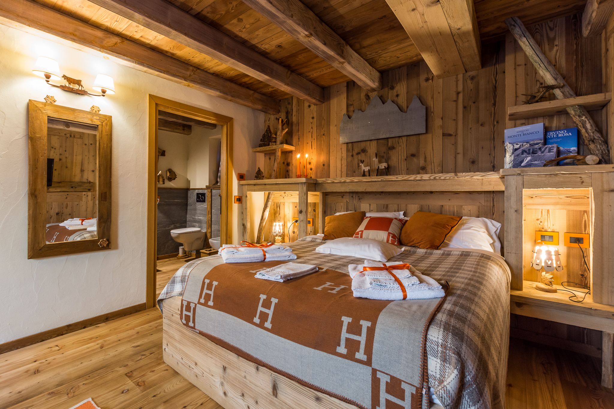 Une chambre à coucher avec un cadre en bois, comprenant un lit, des serviettes et une étagère avec des livres.