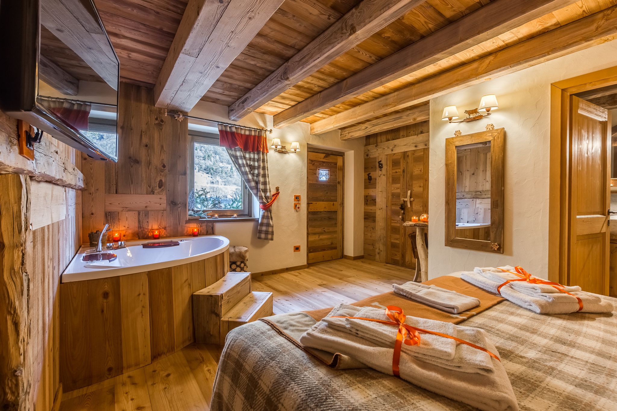L’intérieur d’un chalet en bois comprend une salle de bain, un lit avec des serviettes et un grand miroir.