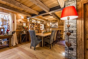 A cozy wooden interior with a dining table, chairs, and a red lamp. - Affittacamere Annie-Parblanc (La Salle)