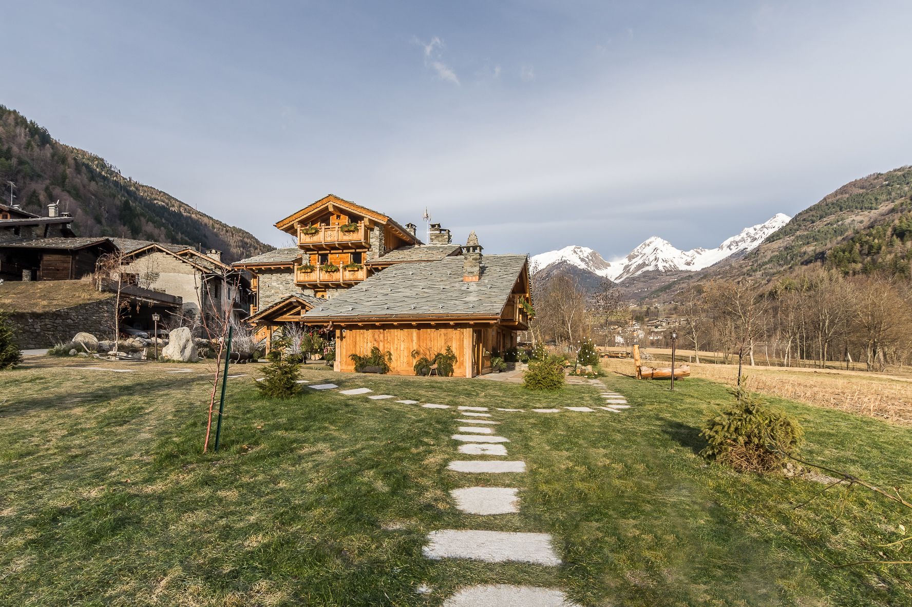 A rustic chalet with a stone facade, wooden balconies, and a stone pathway leading to the entrance.