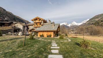 A rustic chalet with a stone facade, wooden balconies, and a stone pathway leading to the entrance.