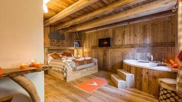 A wooden cabin bedroom with a bed, bedside table, and a small kitchenette.