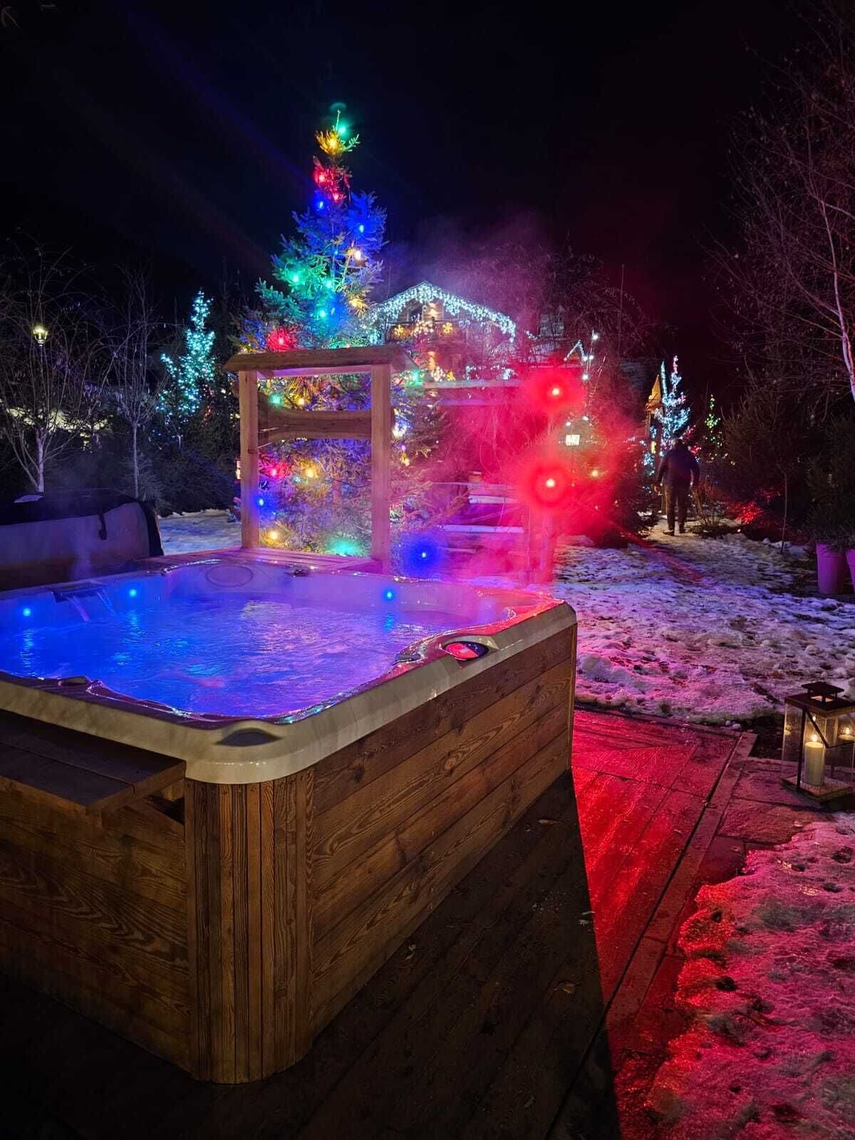 A hot tub with a wooden frame, surrounded by a snow-covered deck.