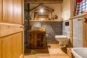 A rustic bathroom with wooden cabinetry, a stone sink, and a white toilet. - Affittacamere Annie-Parblanc (La Salle)