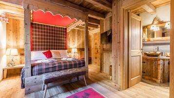 Una cabaña de madera con una cama, un banco, un cabecero rojo a cuadros, un televisor y un gabinete de madera con un lavamanos.