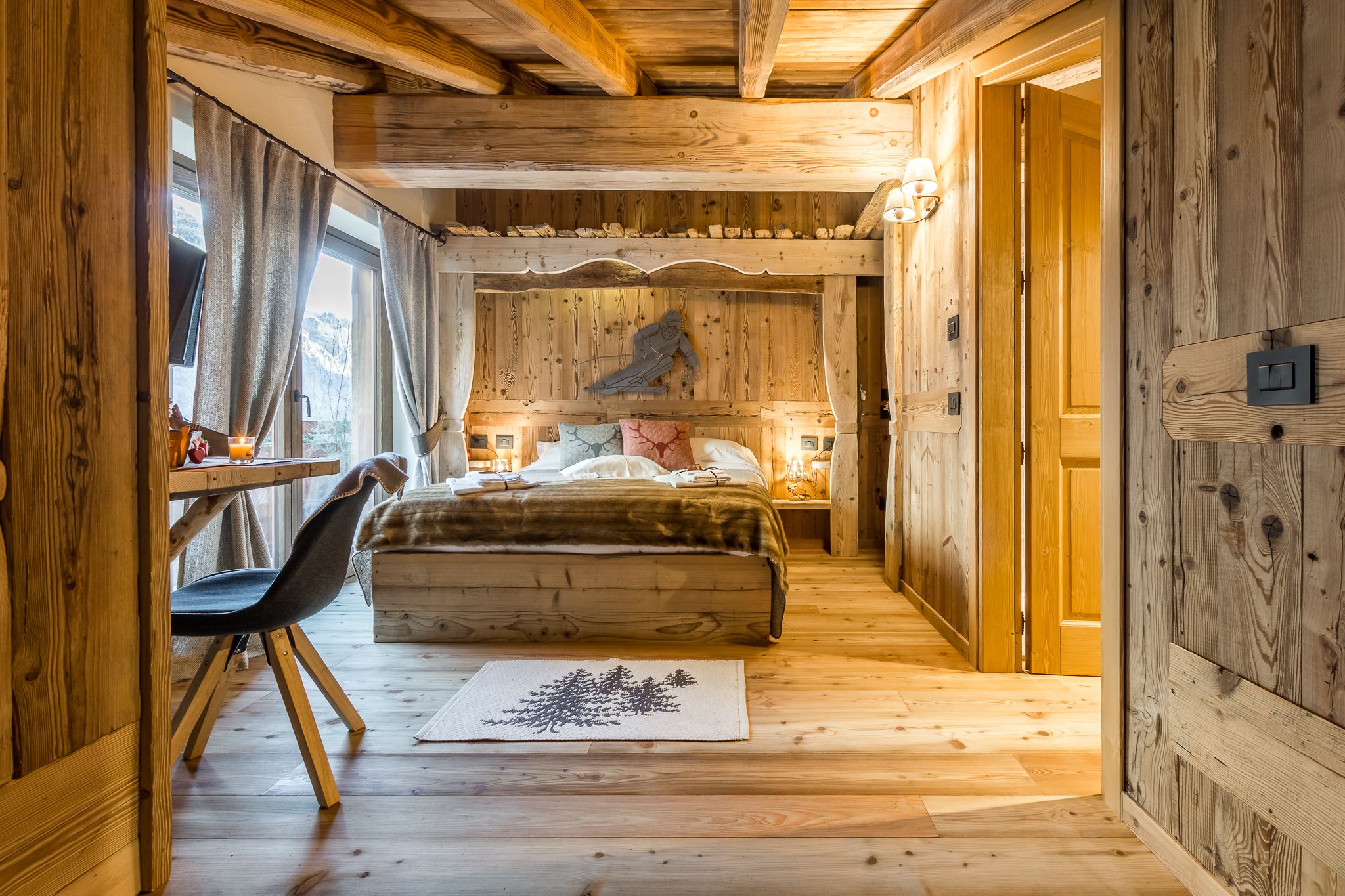 A wooden interior with a bed, a desk, and a chair.
