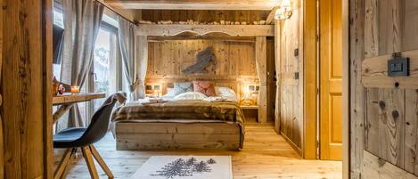 A wooden interior with a bed, a desk, and a chair.