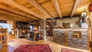 A rustic interior with exposed wooden beams, a stone fireplace, and a cozy seating area. - Affittacamere Annie-Parblanc (La Salle)