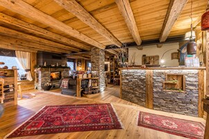 A rustic interior with exposed wooden beams, a stone fireplace, and a cozy seating area.
