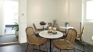 A dining area with wicker chairs, a round table, and a ceiling light fixture. - Hotel Zand (Zandvoort)
