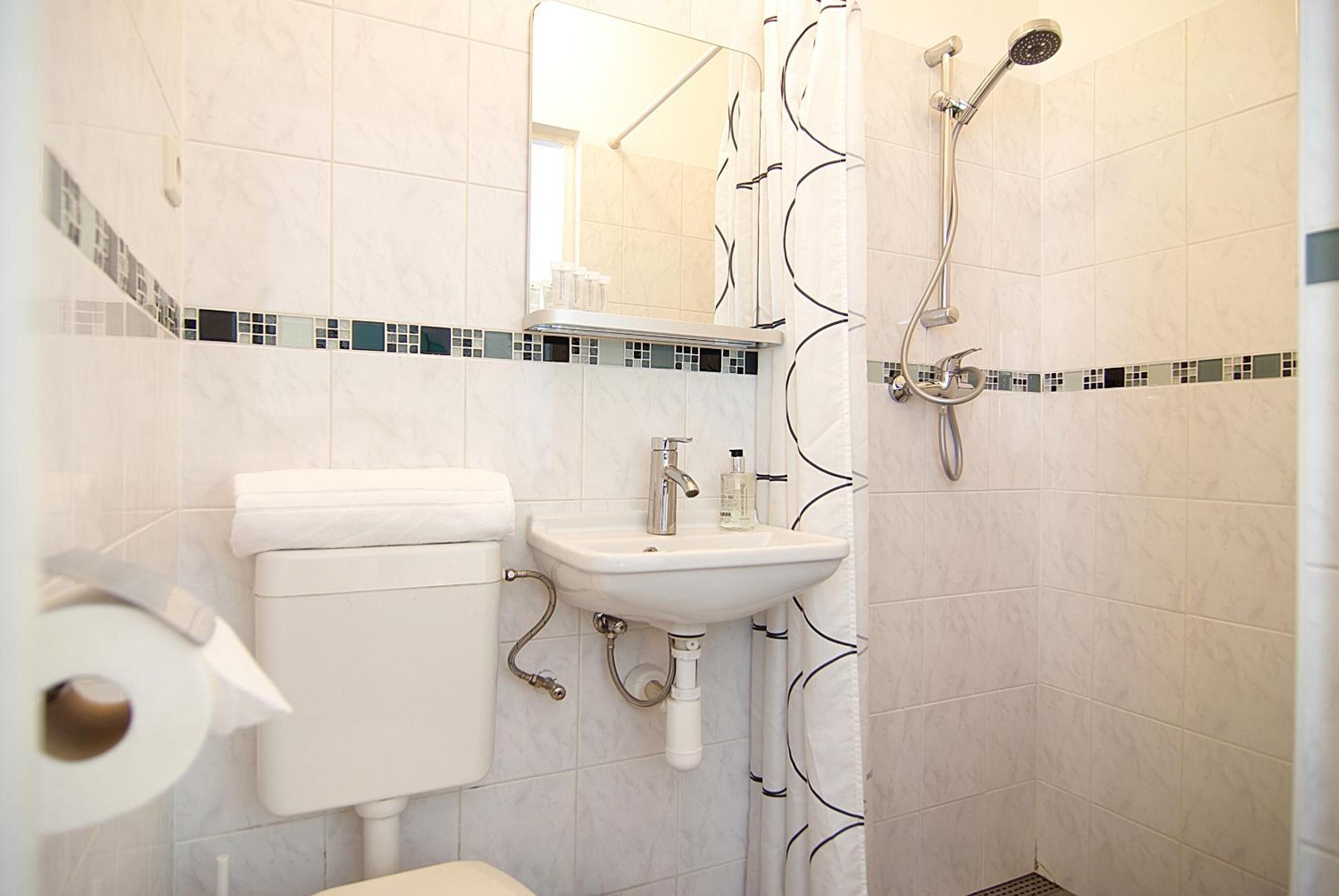 Un baño con inodoro, lavamanos y ducha.