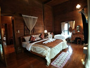 Una habitación amplia con una cama grande, un aparador de madera, un tocador con espejo y un taburete pequeño.