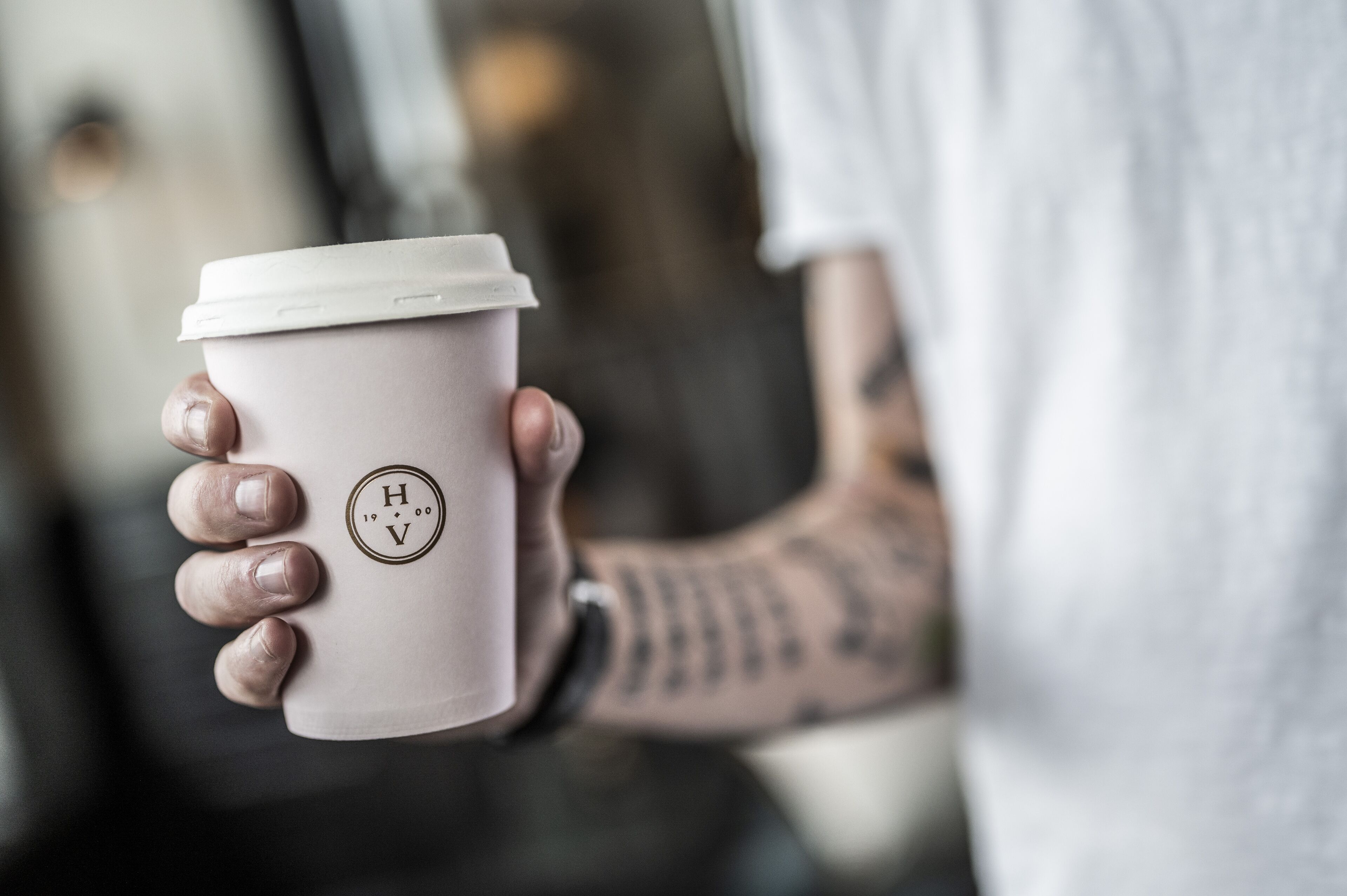 A person holding a coffee cup with a logo.