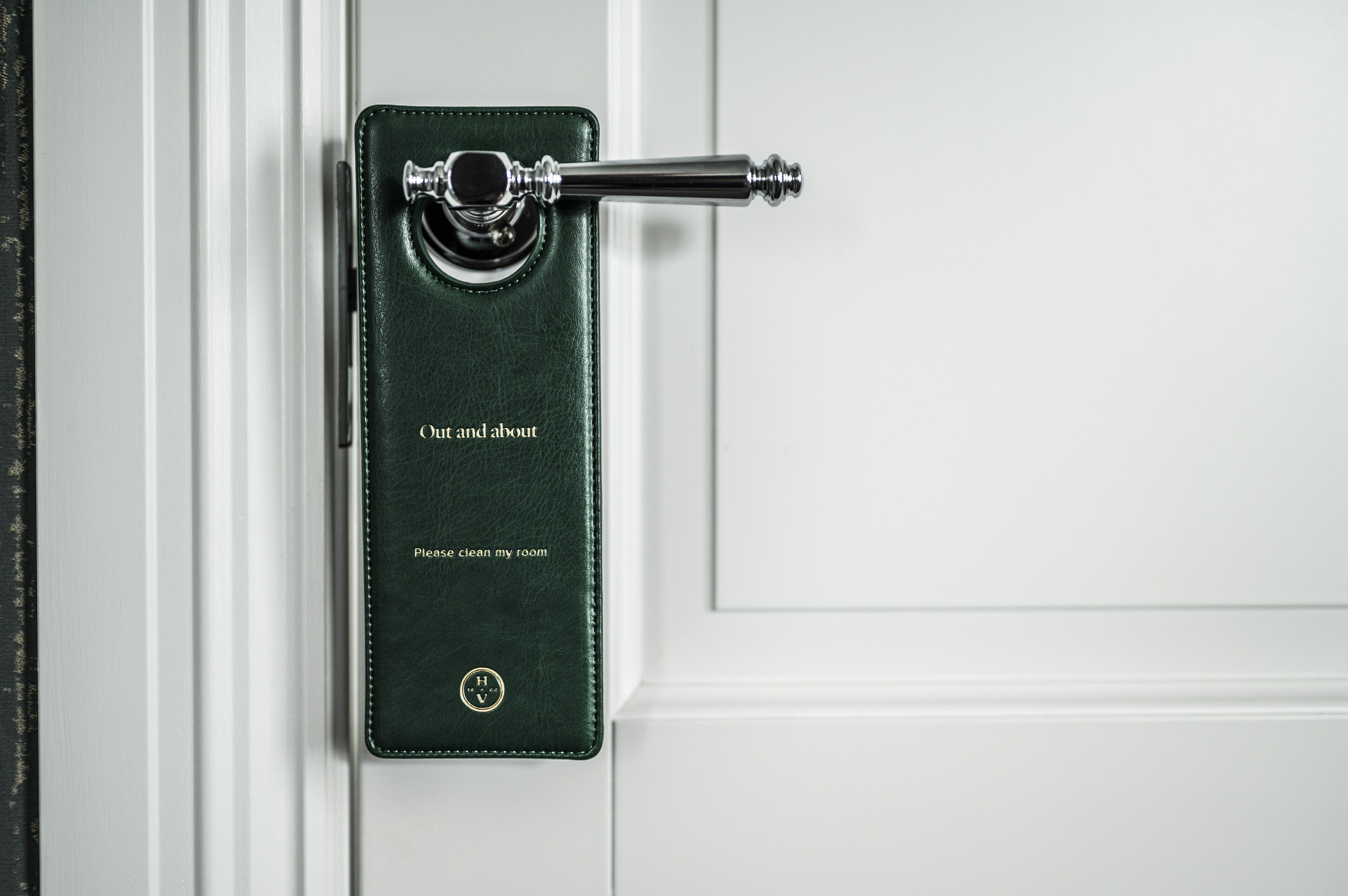 A green leather-bound book with the text "Out and about" and "Please clean my room" on a door handle.