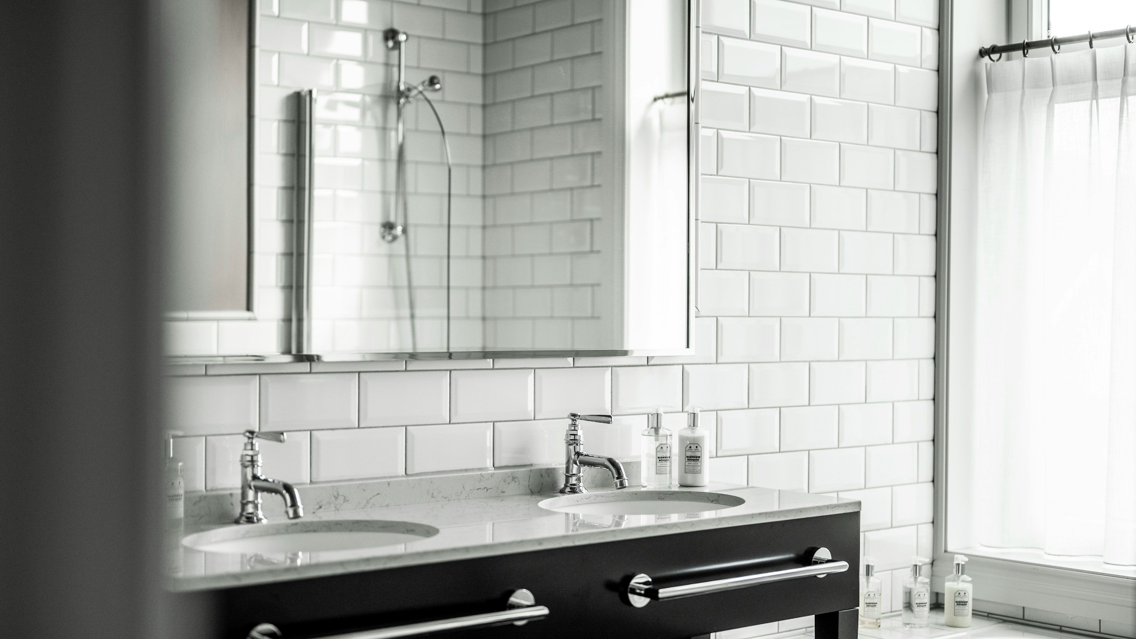 A bathroom with two sinks, a mirror, and a shower.