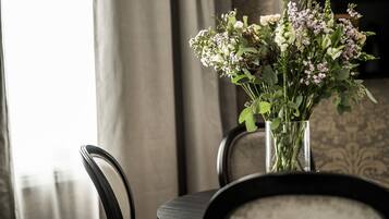 Et bord med en vase blomster, to stole og en tapetvæg i baggrunden.