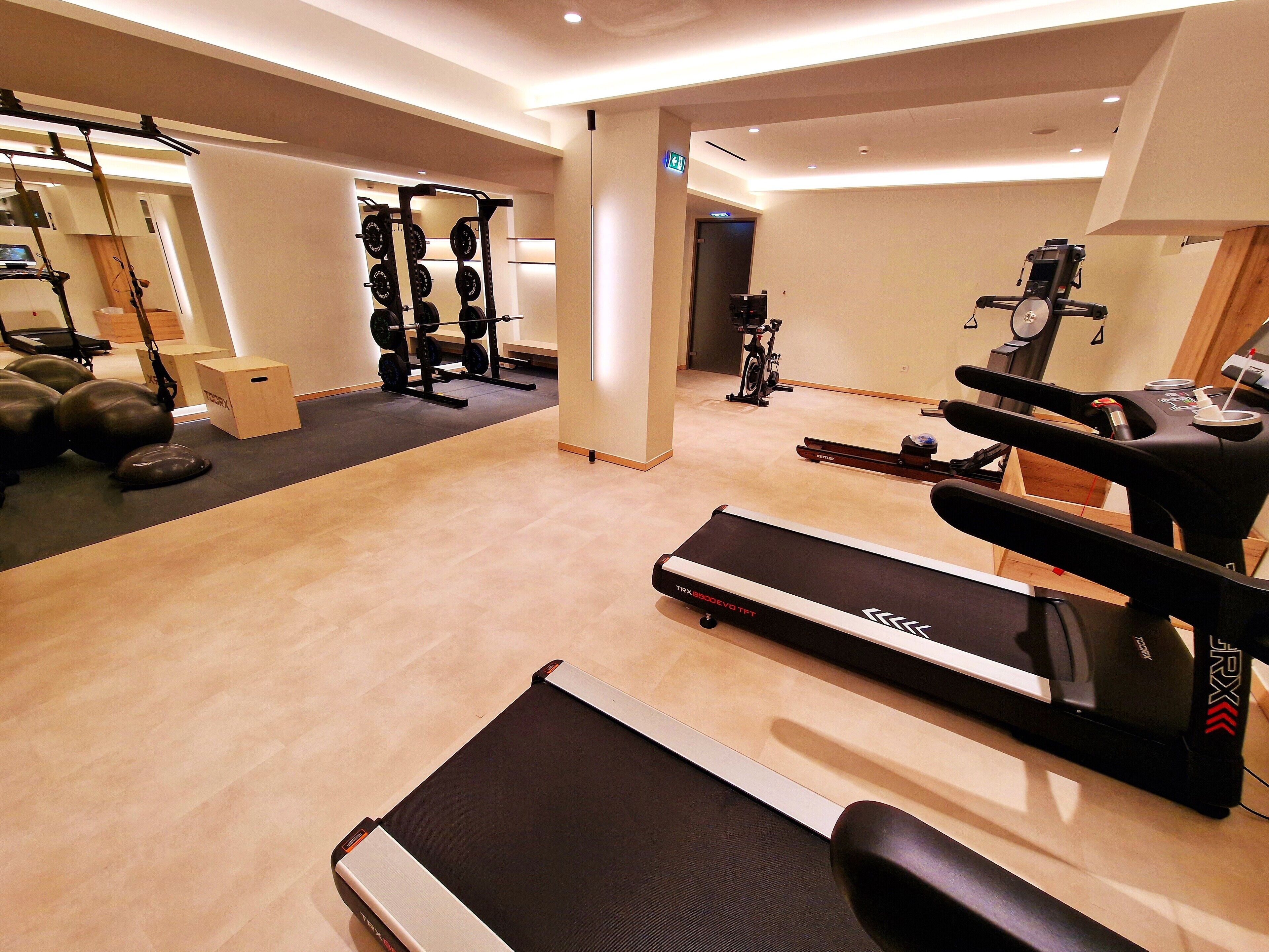 A gym with treadmills, a weightlifting station, and exercise balls.
