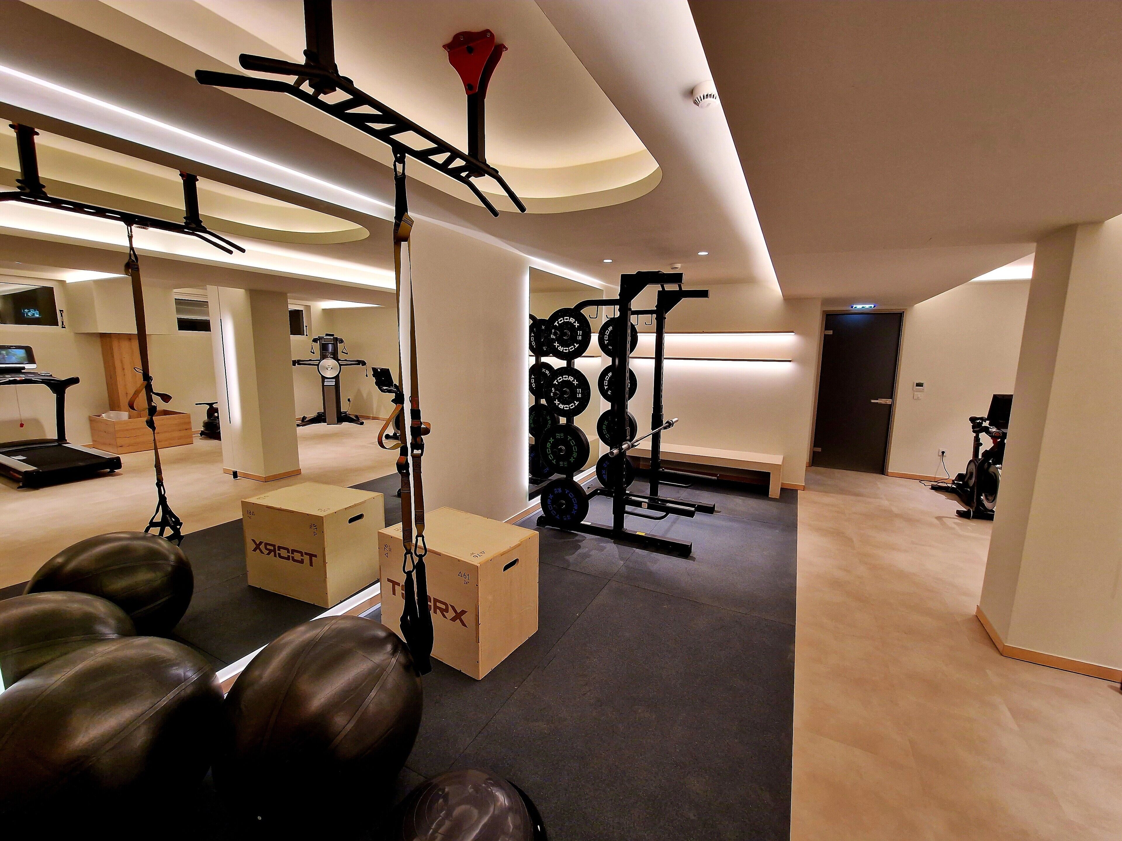 A modern gym with exercise equipment, a treadmill, and weightlifting stations.