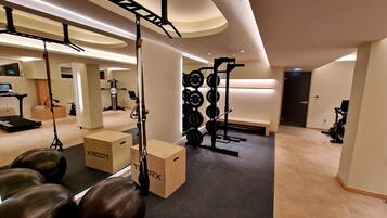 A modern gym with exercise equipment, a treadmill, and weightlifting stations.