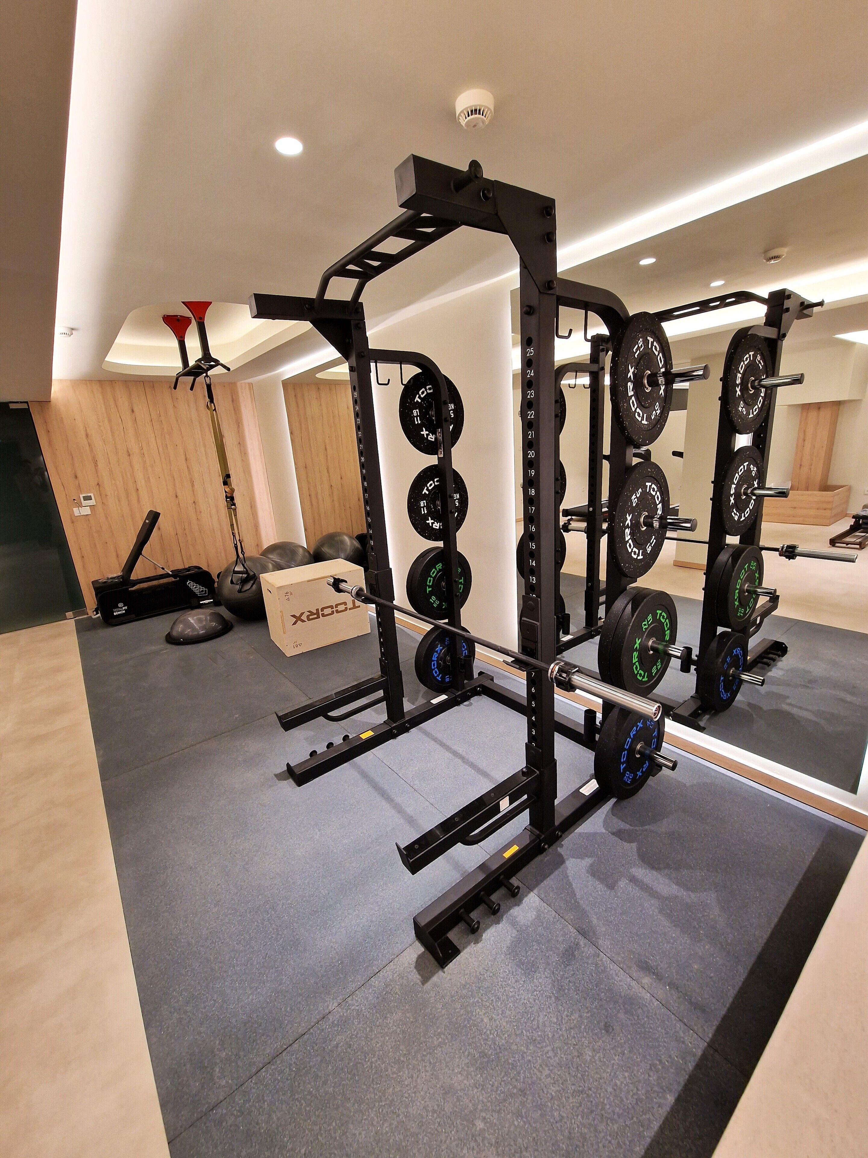 A gym with weightlifting equipment, a mirror, and a wooden wall.