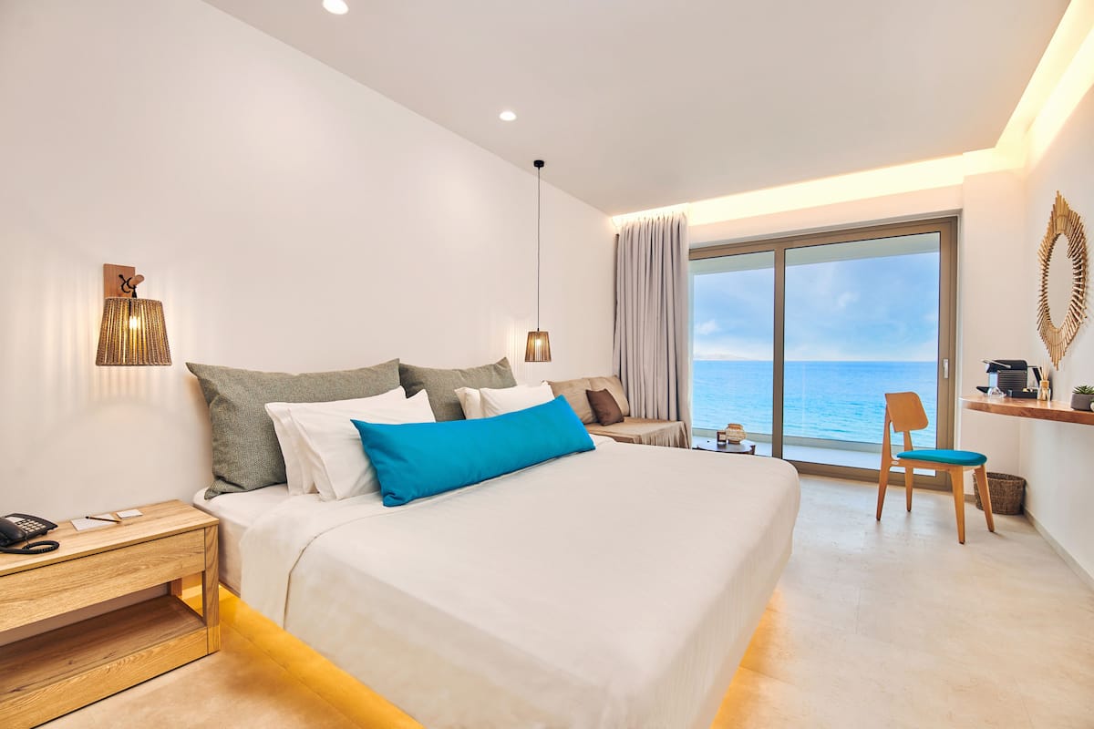 Una habitación de hotel moderna con una cama grande, un escritorio y vista al mar.