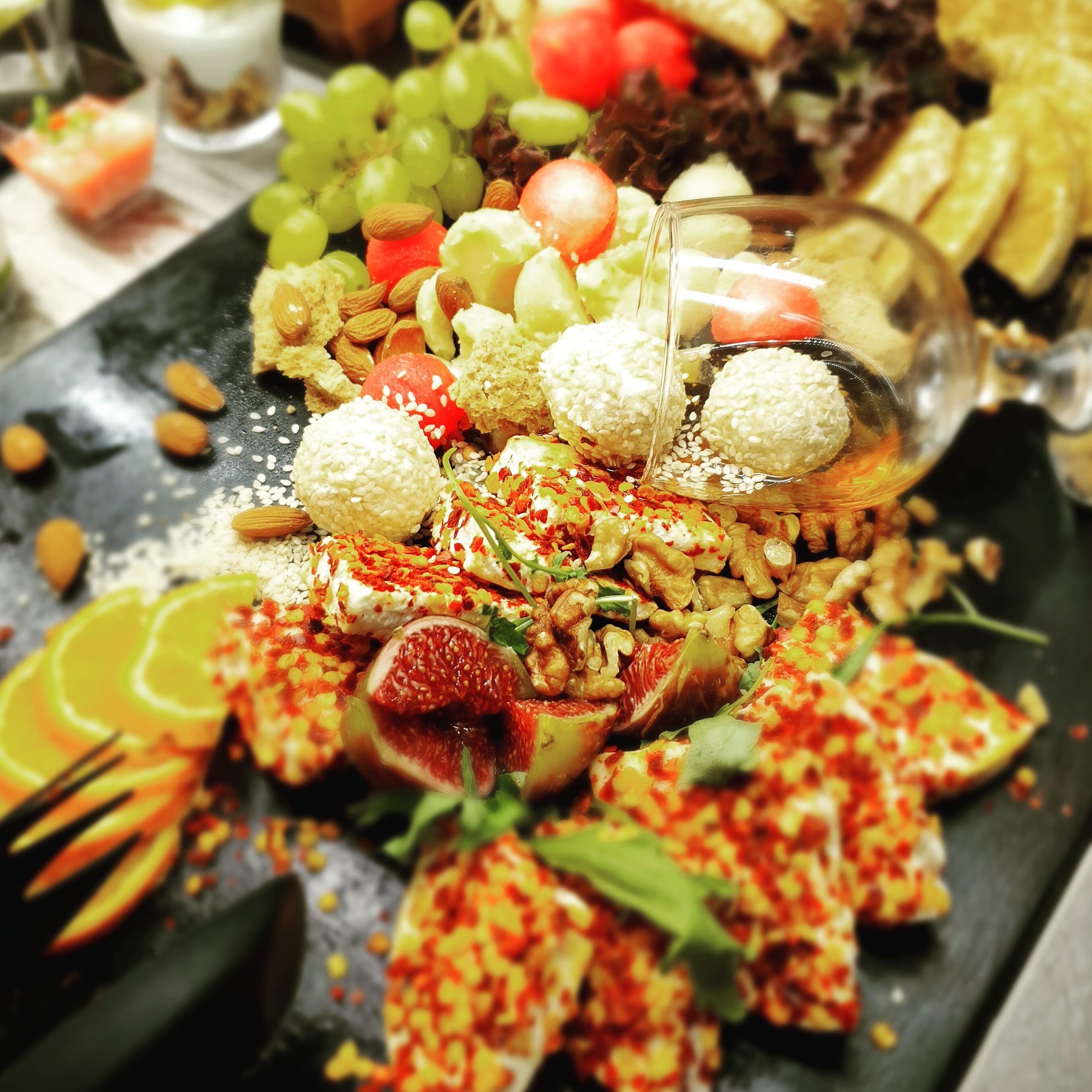 A variety of food items including fruits, nuts, and cheese on a black slate board.