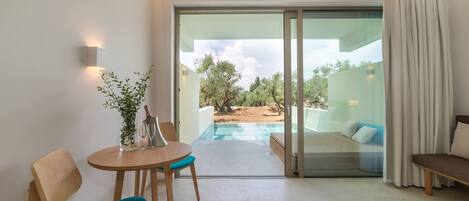 A modern room with a glass door leading to an outdoor pool area, a wooden table with chairs, and a sofa.
